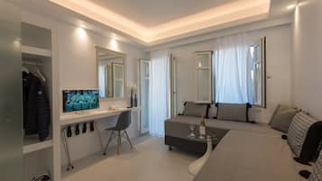 A modern hotel room with a bed, a desk with a computer, a chair, and a TV.