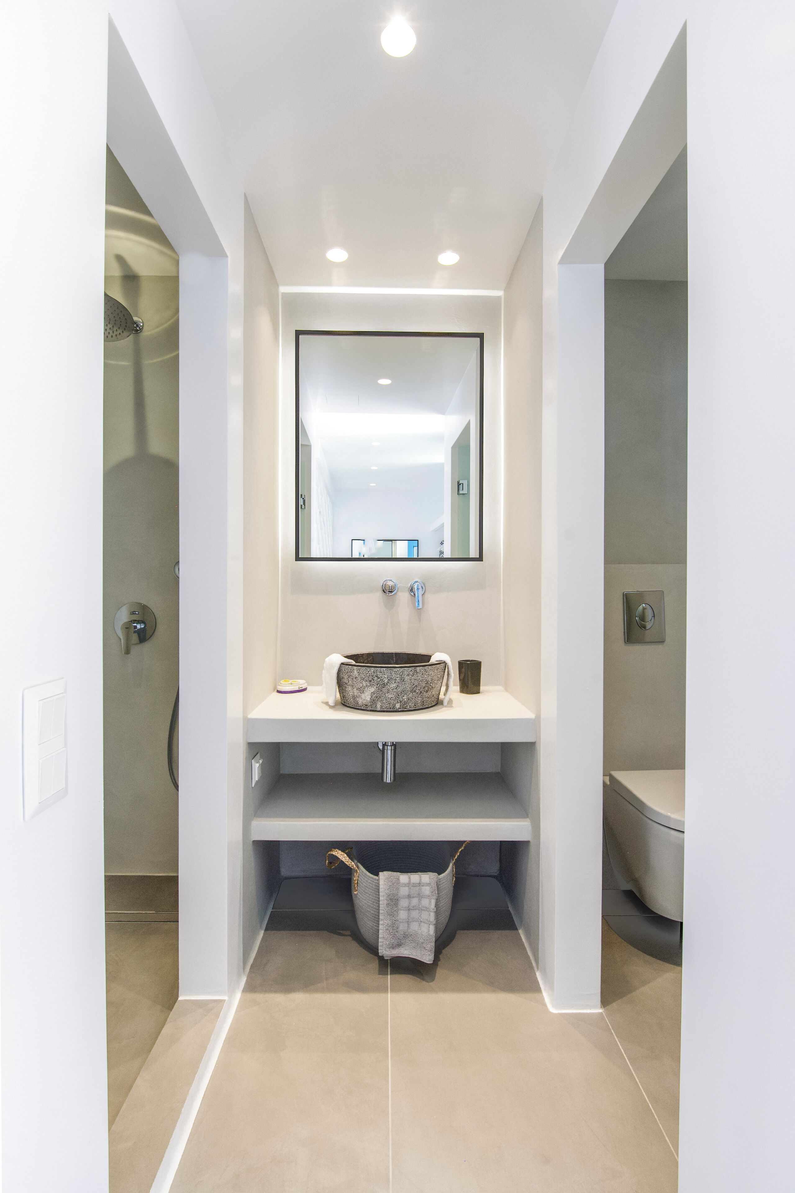A modern bathroom with a built-in sink, a mirror above it, and a shower area to the left.