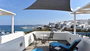 Enjoy a tranquil view of the coastal town from this terrace with a table, chairs, and lounge seating.