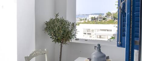 A white table with two chairs, a potted plant, and a decorative item on the table.
