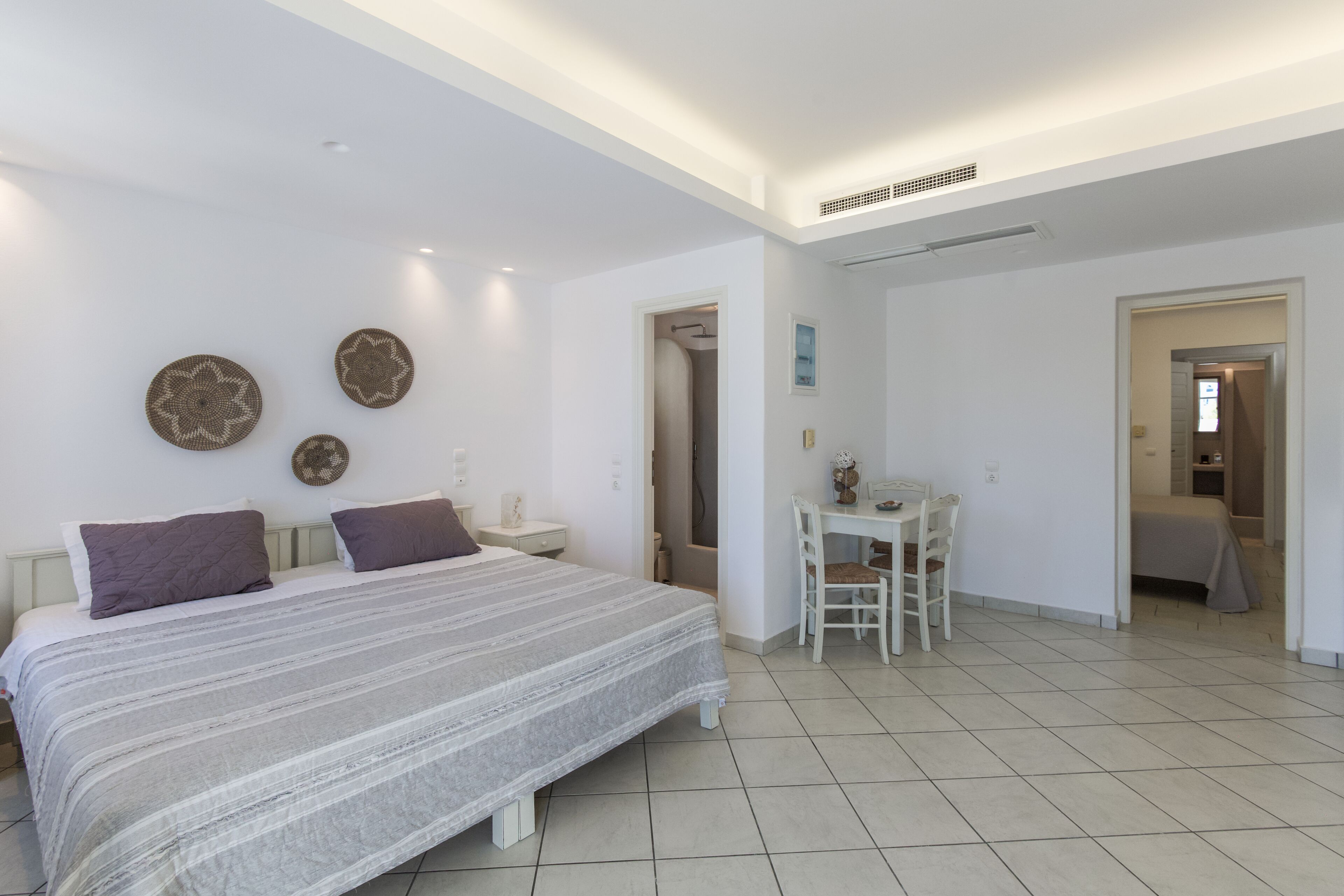 A bedroom with a bed, bedside tables, a desk, and a chair. There are doors leading to other rooms.