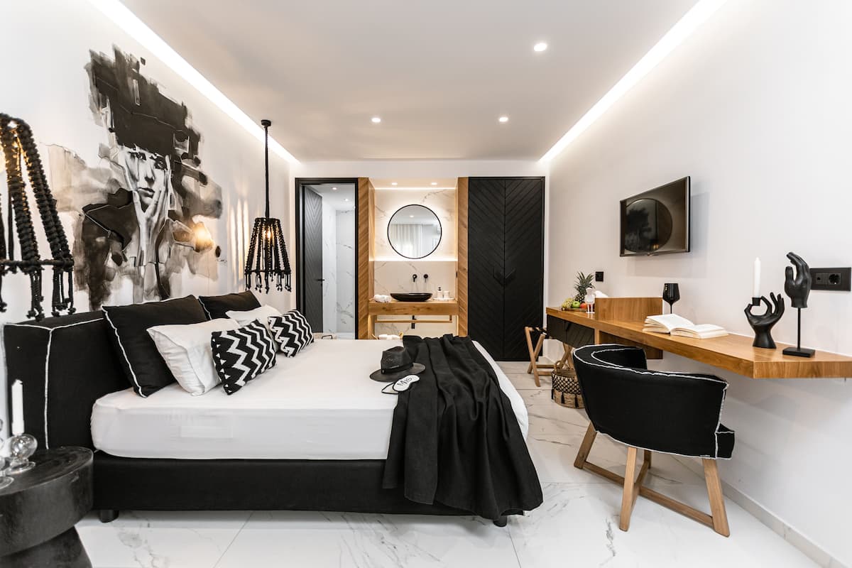 Quarto moderno com cama, mesa de cabeceira e área de escritório.