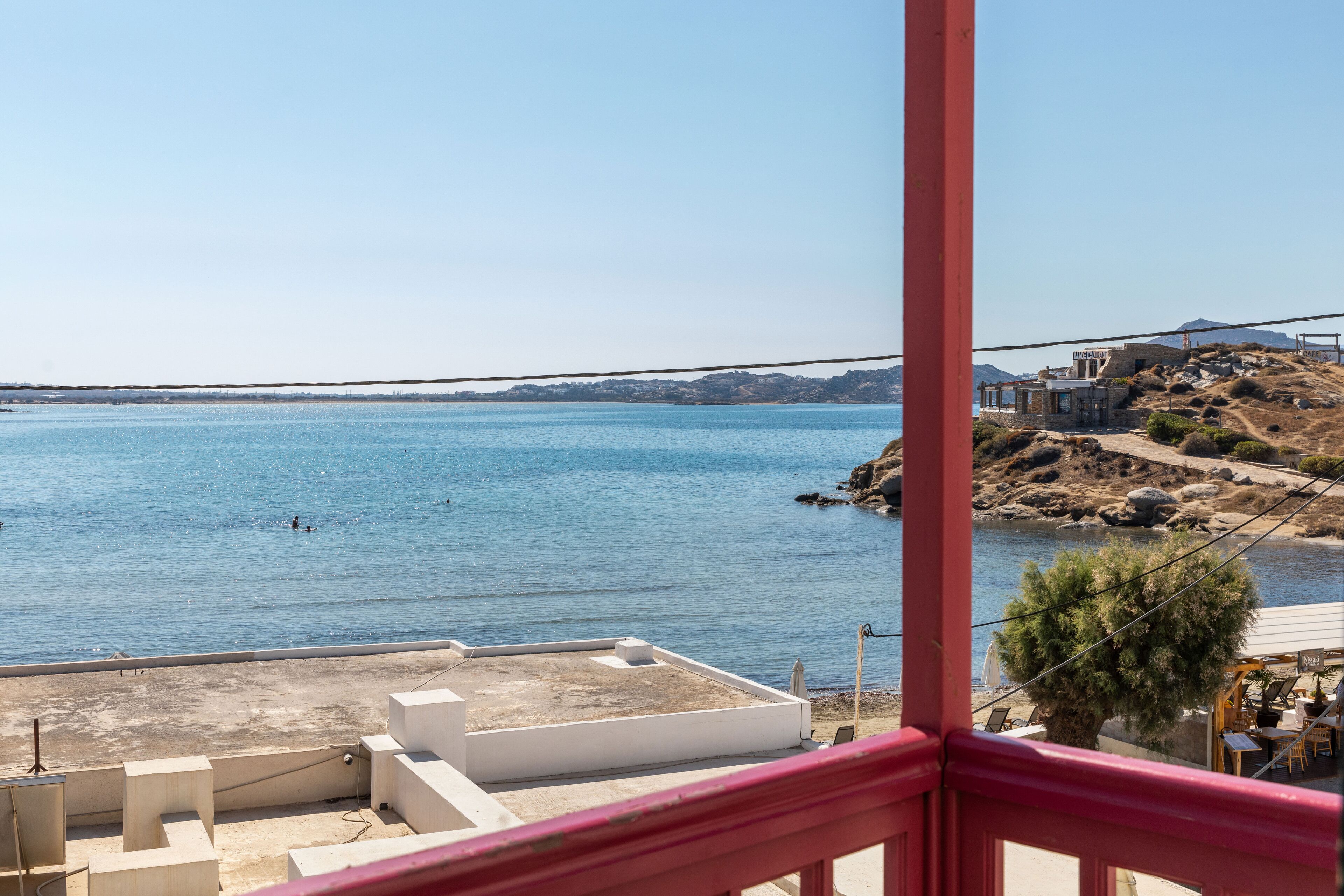 A coastal view with a clear sky, a body of water, and a distant rocky landscape.