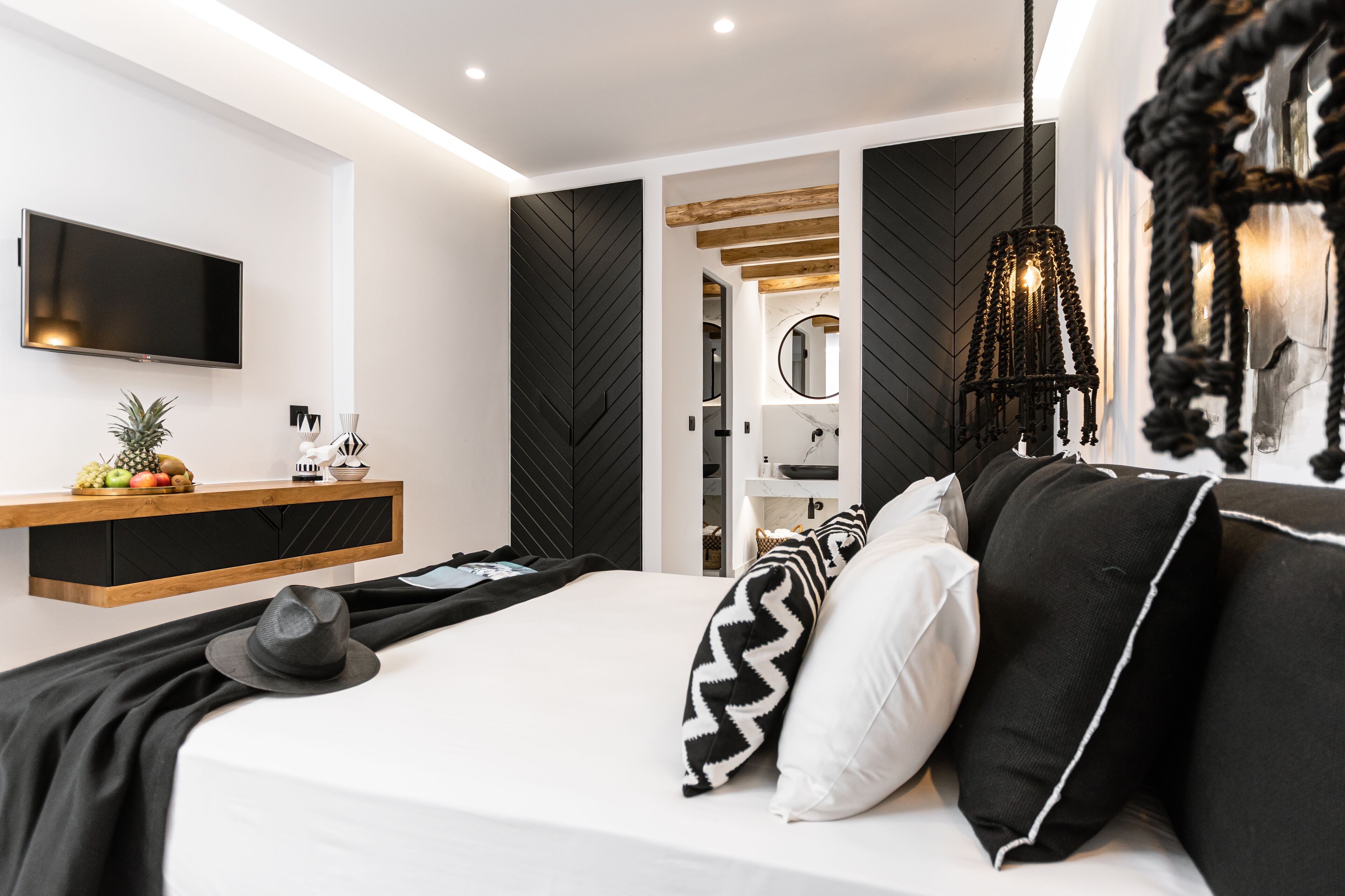 A modern bedroom with a bed, a TV, and a wooden shelf with fruits.