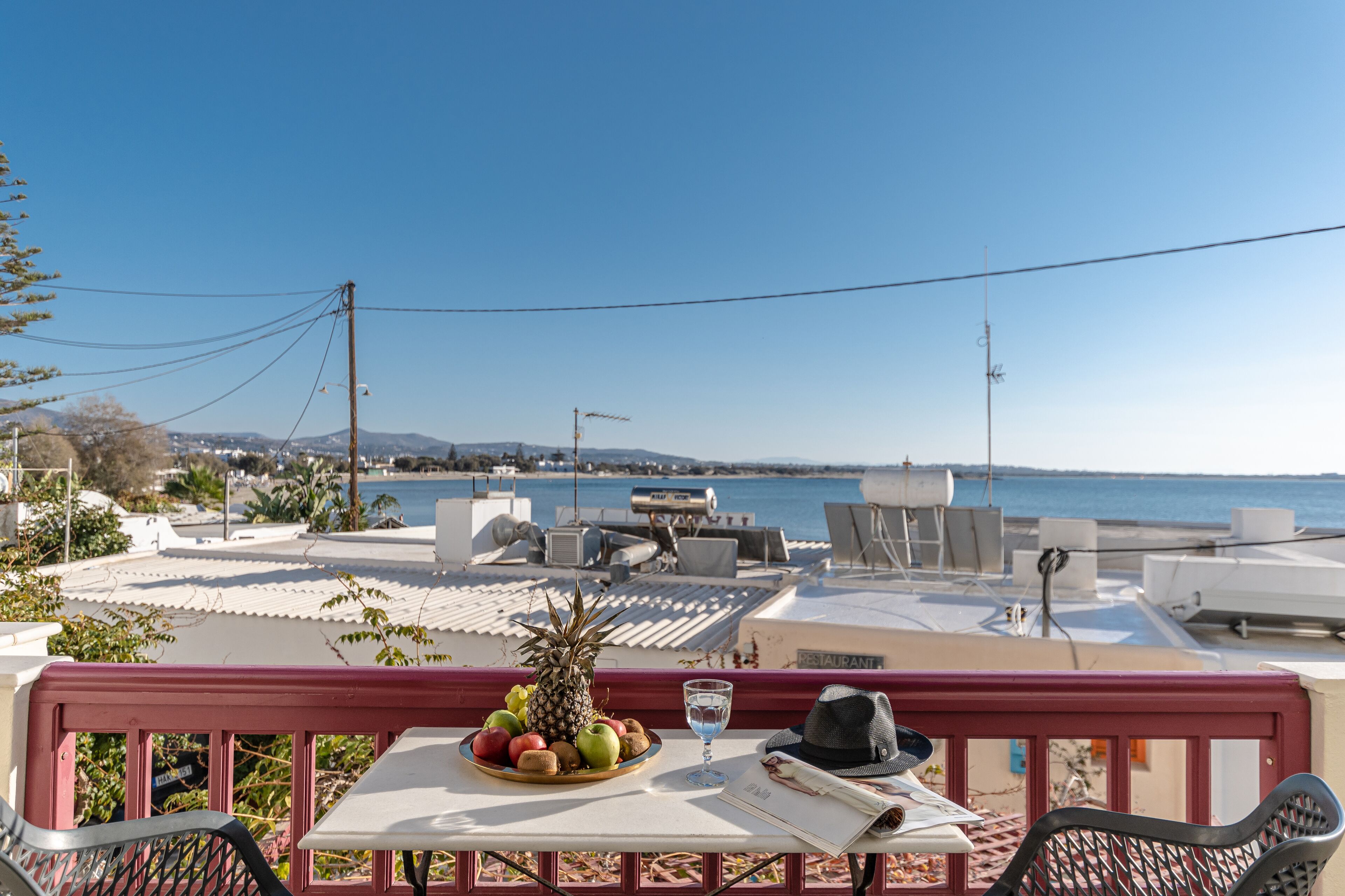A terrace with a table set for dining, overlooking a coastal view.