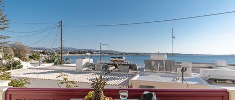 A terrace with a table set for dining, overlooking a coastal view.