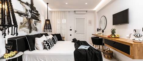 A modern bedroom with a black and white color scheme, a bed, bedside table, and a wooden console table with fruit.