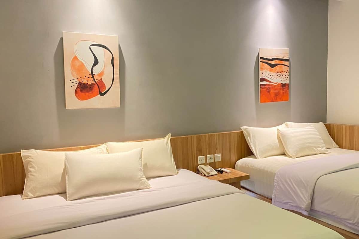 Habitación de hotel con dos camas, cabecero de madera, mesita de noche con teléfono y obras de arte abstracto en las paredes.