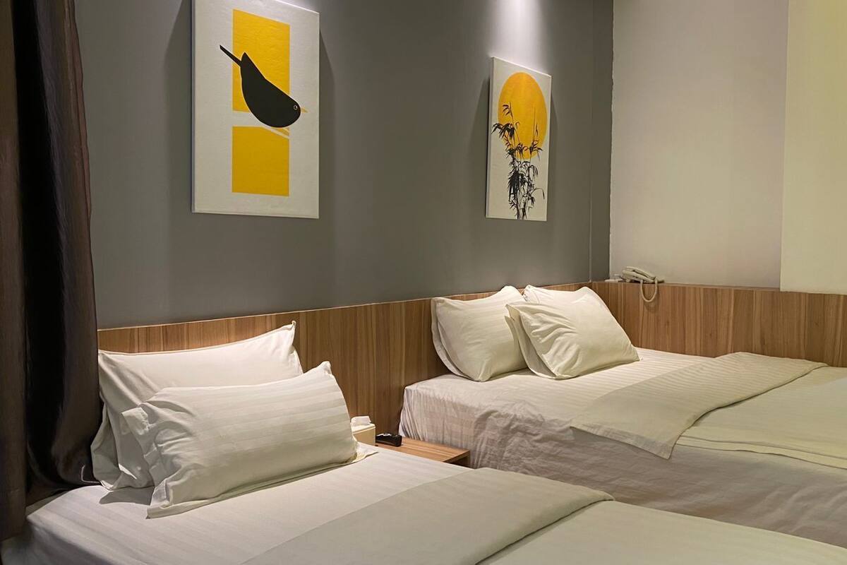 Habitación de hotel con dos camas, cabecera de madera y una obra de arte en la pared.