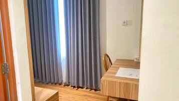 A room with a wooden dining table, a chair, and a window with blue curtains.