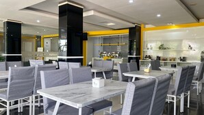 A modern restaurant with marble tables and grey upholstered chairs. - Kaliban Hotel (Batam)