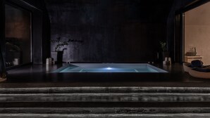 A modern spa area with a rectangular hot tub, dark wooden flooring, and minimalist decor. - Argo Boutique Hotel (Naxos)
