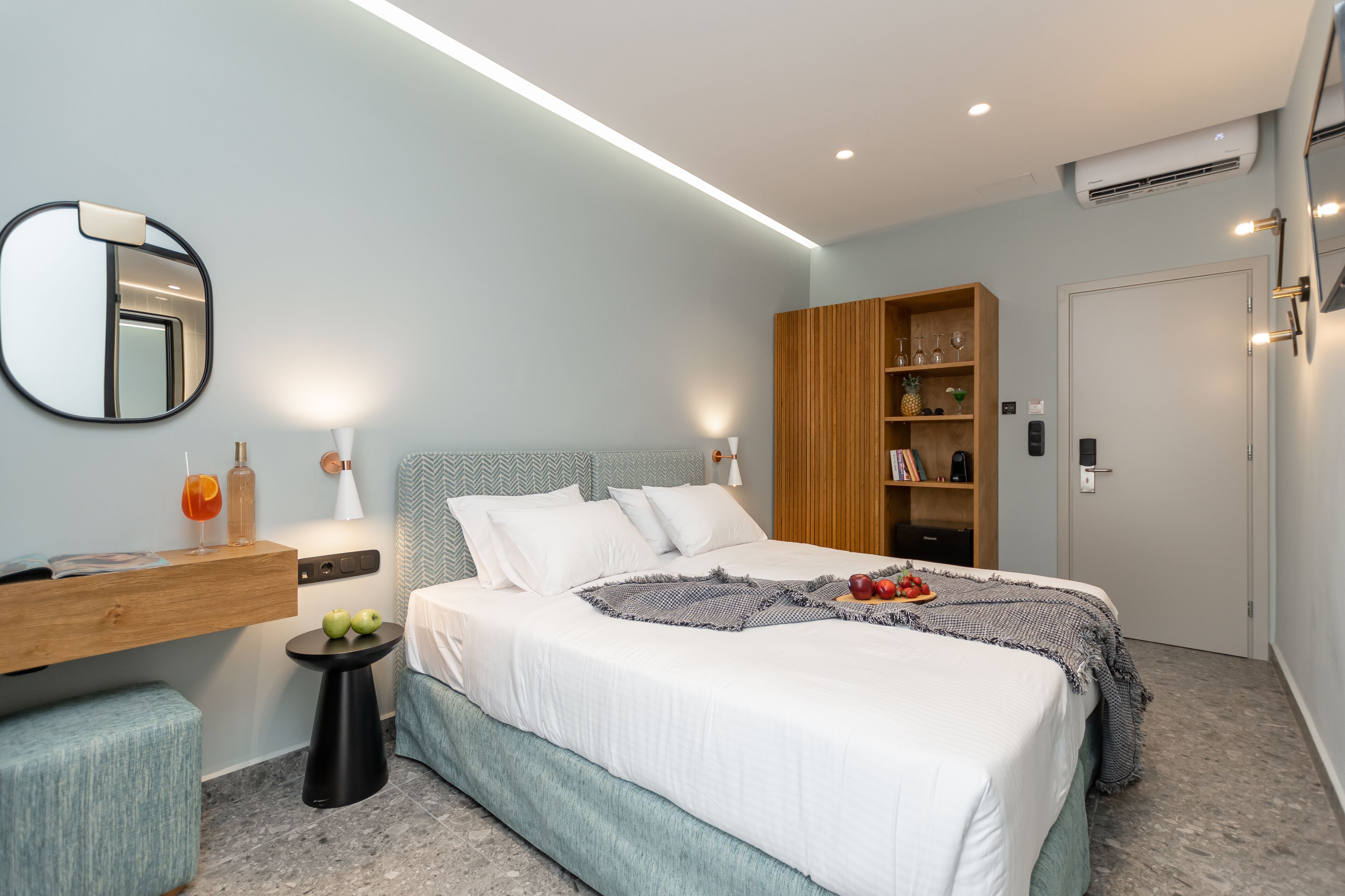 A modern bedroom with a bed, bedside table, mirror, and built-in wardrobe.