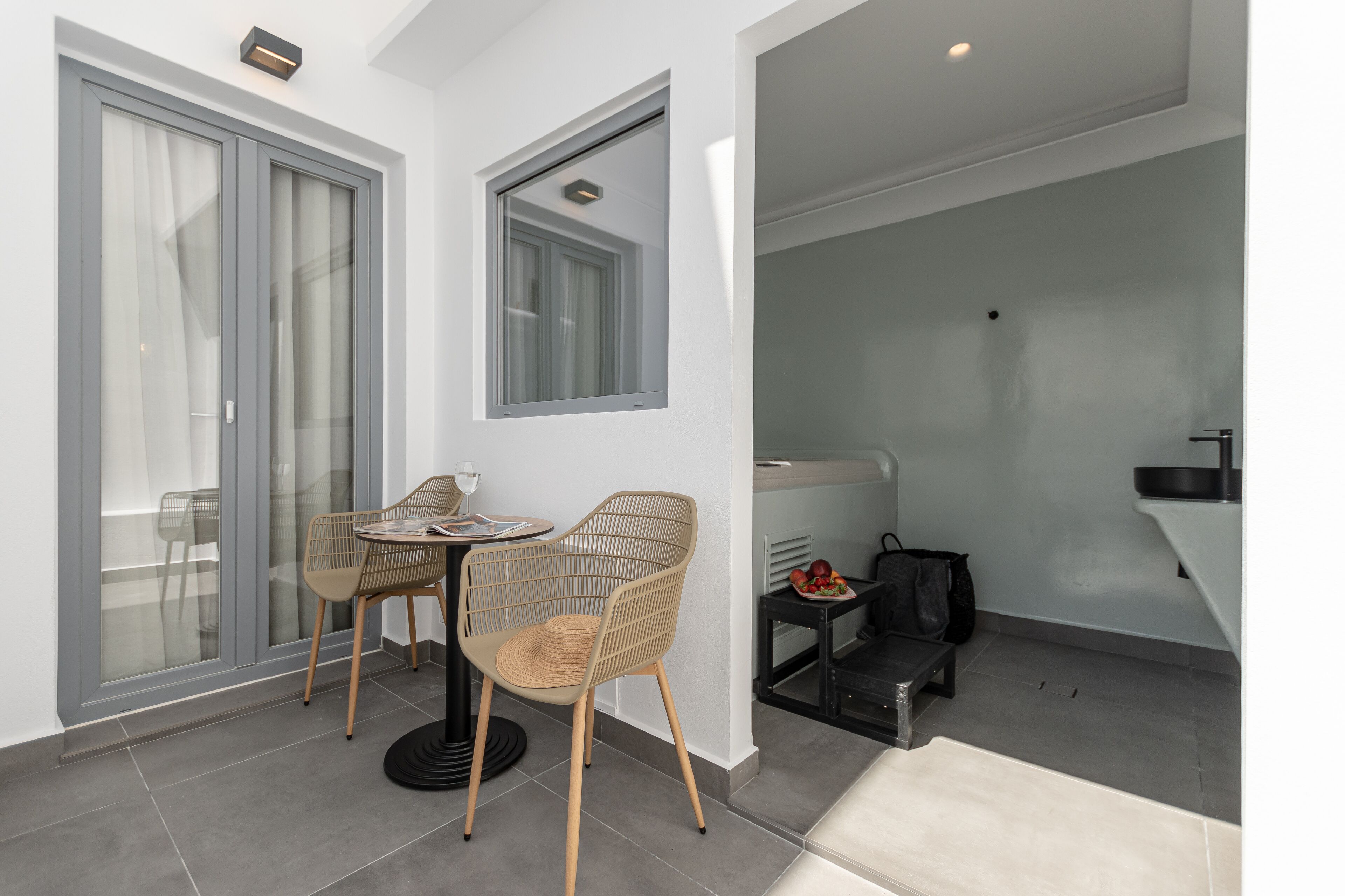 A modern living area with a dining table and chairs, a small kitchen area, and a sliding glass door leading to an outdoor space.