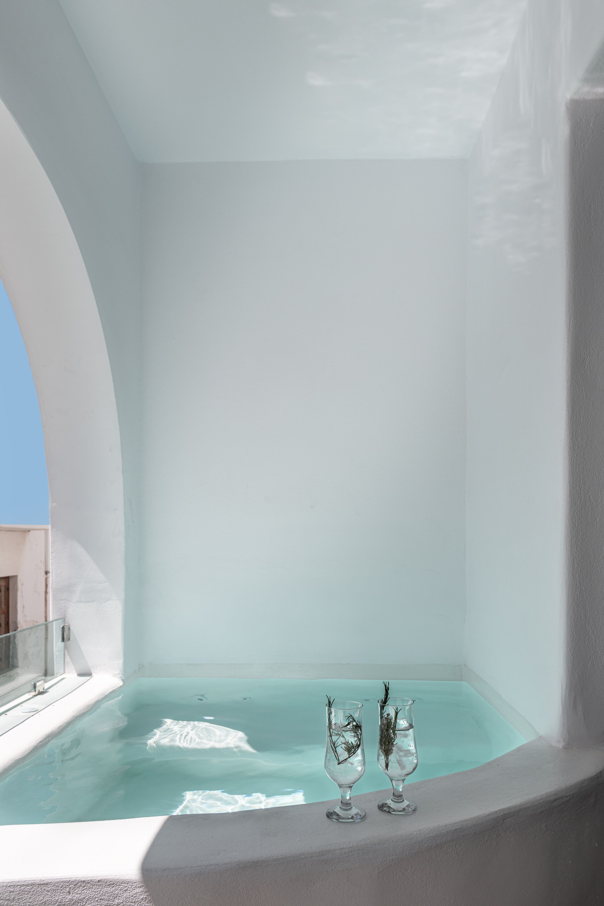 A spa area with a large bathtub and two glass vases with plants.