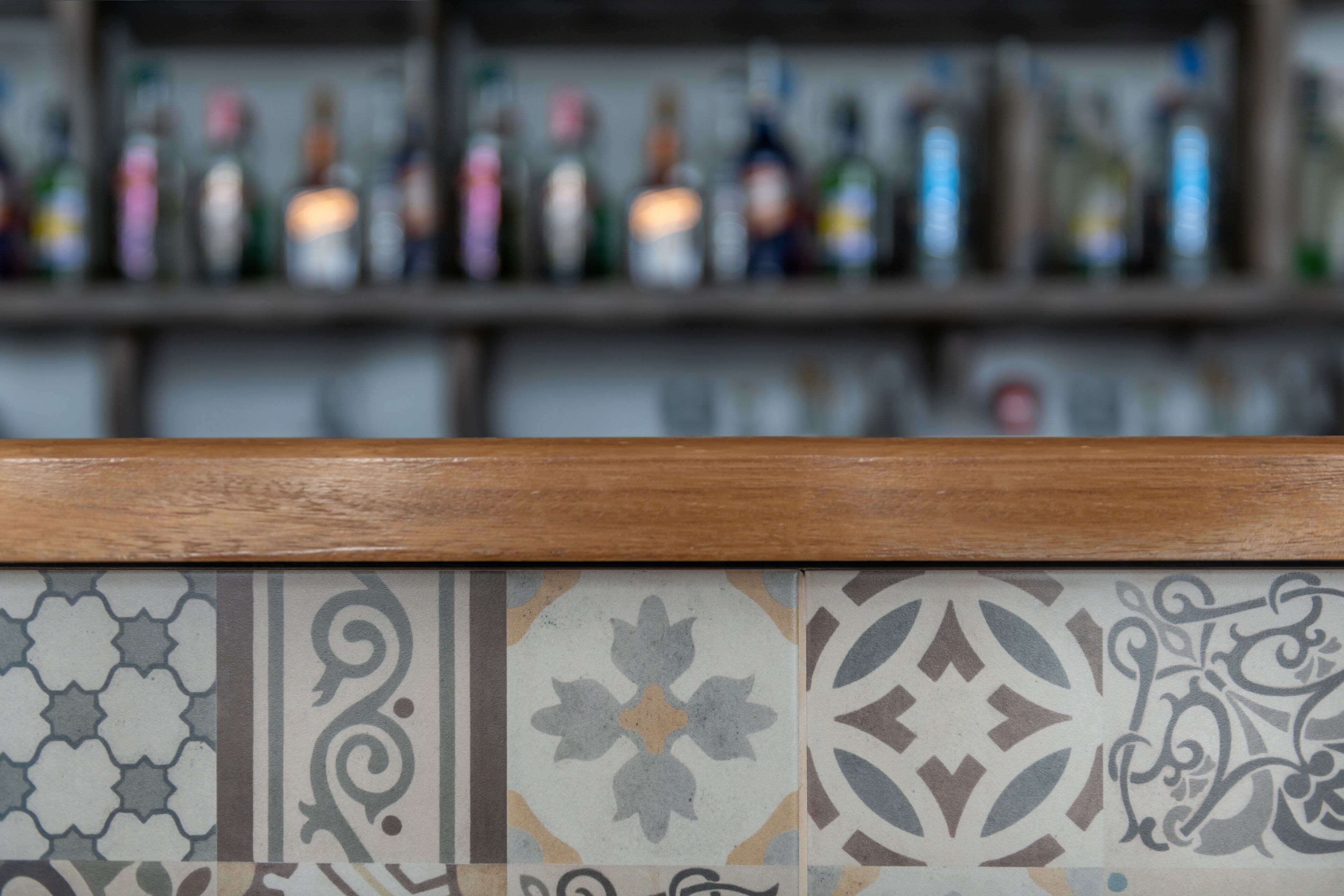 A bar area with a tiled backsplash and shelves with bottles.