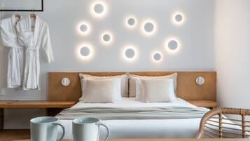 A hotel room with a bed, bedside table, two mugs, and a wall with circular light fixtures.