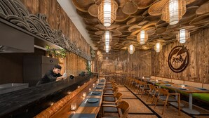 A restaurant with a long counter, wooden walls, and hanging lights. - Montigo Resorts Seminyak (Keroboken Kelod)
