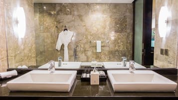 A bathroom with two sinks, a robe hanging, and a towel rack.