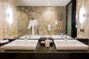 A bathroom with two sinks, a robe hanging, and a towel rack.