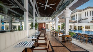 A spacious outdoor dining area with multiple tables and chairs, a pool, and a covered walkway. - Montigo Resorts Seminyak (Keroboken Kelod)