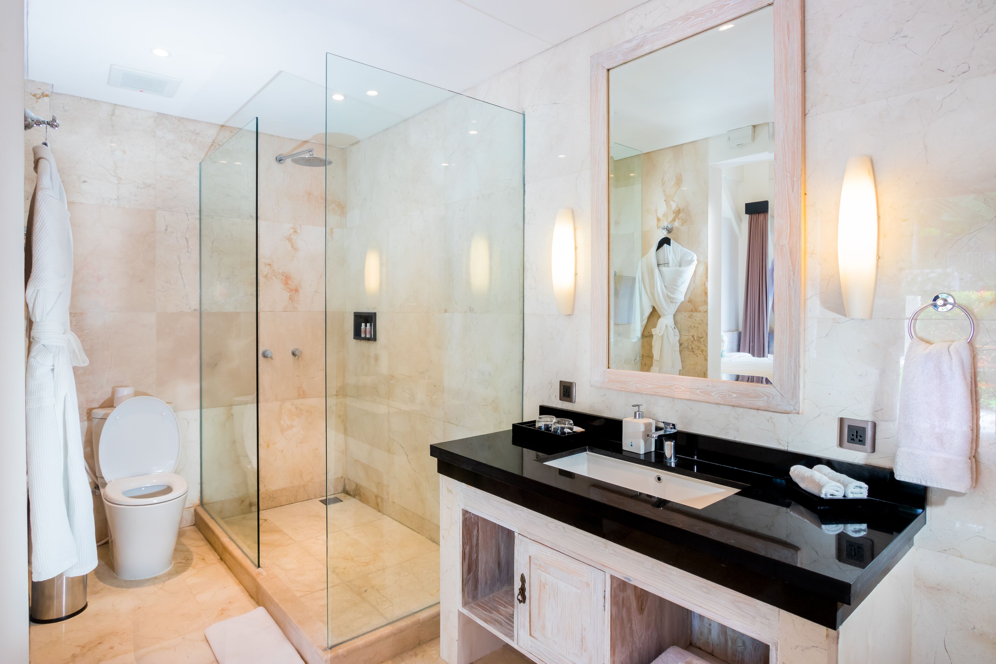 A modern bathroom with a glass-enclosed shower, a black countertop sink, and a large mirror.
