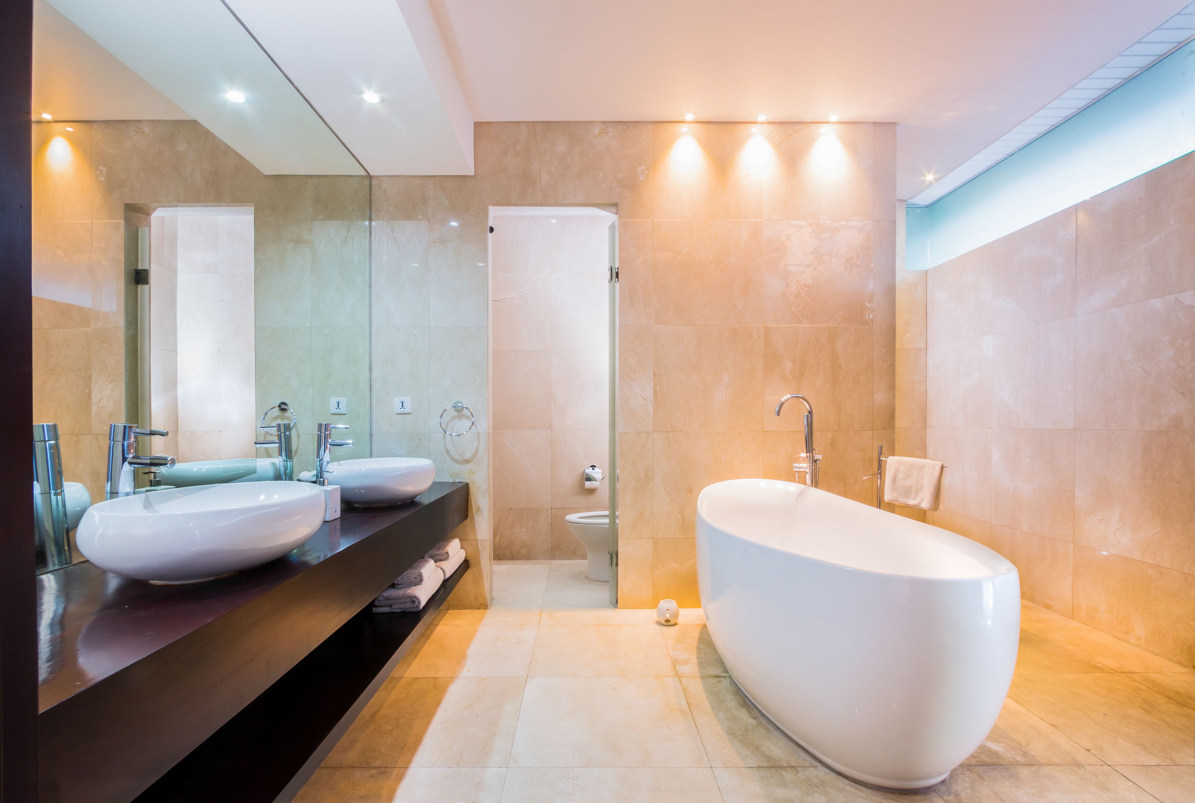 A modern bathroom with a large bathtub, two sinks, and a toilet.