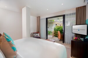 Et moderne hotelværelse med en stor seng, et fjernsyn og udsigt til en have gennem skydedøren.