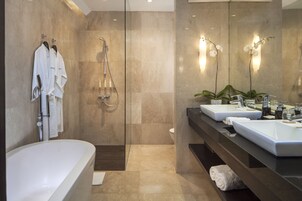 A modern bathroom with a large bathtub, two sinks, and a shower.
