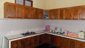 A kitchen with wooden cabinets, a gas stove, and a tiled backsplash.