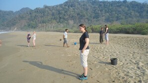 A sandy beach with footprints and a few people standing.