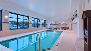 An indoor swimming pool with clear windows, a poolside seating area, and a view of a parking lot. - TownePlace Suites by Marriott Des Moines West/Jordan Creek (West Des Moines)