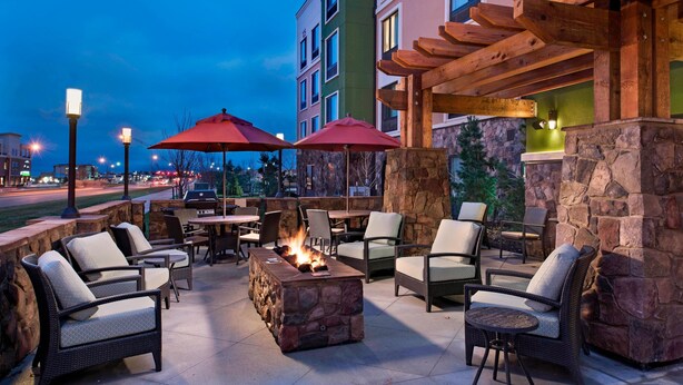 An outdoor patio area with stone walls, wicker furniture, and a fire feature. - TownePlace Suites by Marriott Des Moines West/Jordan Creek (West Des Moines)