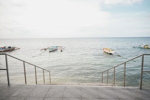 A view of a calm sea with boats anchored near a staircase leading to a pier.