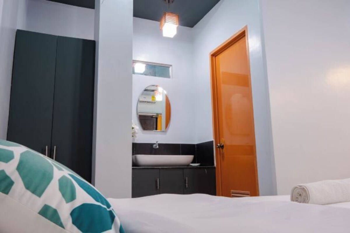 Un dormitorio con cama, armario, espejo y baño con lavabo e inodoro.