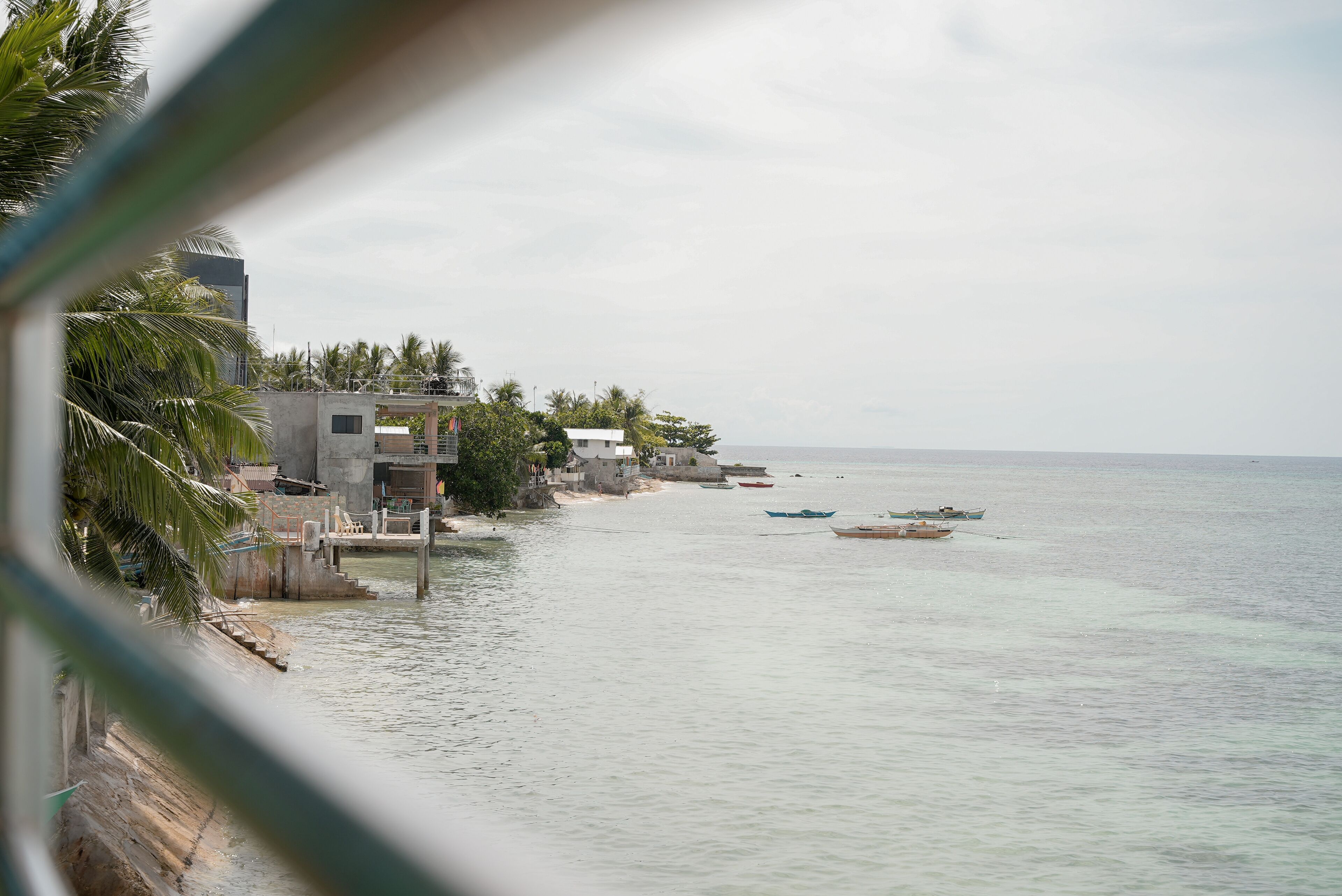 Vista costeira com edifícios, praia e barcos.