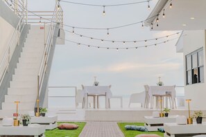 A modern outdoor terrace with a staircase, white furniture, and string lights.
