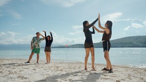 Un groupe de personnes se trouve sur une plage, avec un drapeau en arrière-plan.