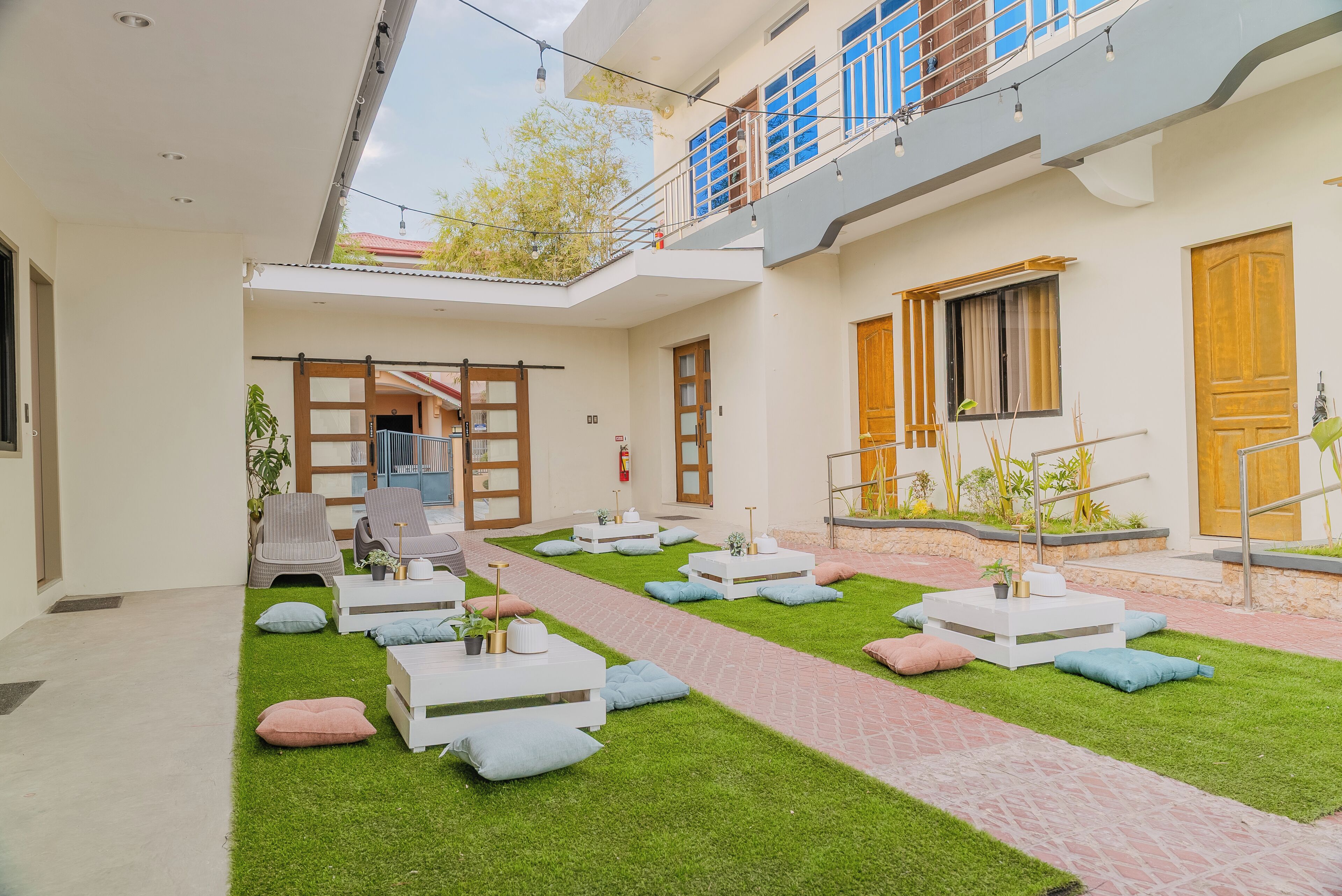 A modern outdoor lounge area with a pathway, seating arrangements, and a small garden.