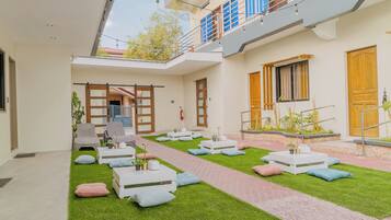 Un espacio lounge moderno al aire libre, con un sendero, arreglos de asientos y un pequeño jardín.