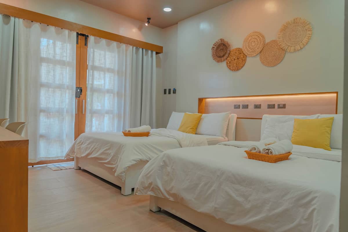 Una habitación de hotel con dos camas, un cabecero de madera y una lámpara fijada a la pared.