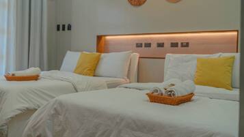 A hotel room with two beds, white bedding, yellow pillows, and a woven wall decoration.