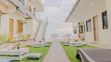 Ein modernes Hotel-Atrium mit einem zentralen Weg, Sitzgelegenheiten im Freien und einer Treppe zu einer oberen Ebene.