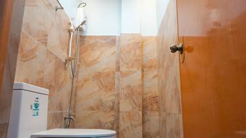 A bathroom with a toilet, shower, and a marble wall.