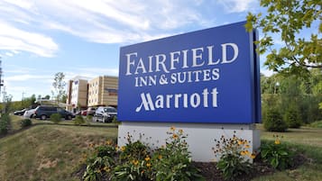 A sign for Fairfield Inn & Suites Marriott with a parking lot and buildings in the background.