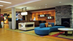 A modern lobby with a blue sofa, a fireplace, and a reception desk. - Fairfield Inn & Suites Stroudsburg Bartonsville / Poconos (Stroudsburg)