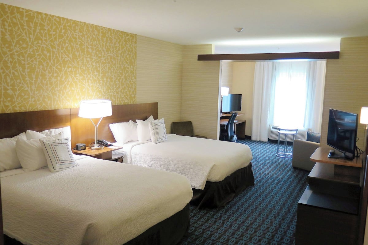 Ett hotellrum med två sängar, ett skrivbord, en stol och en TV.