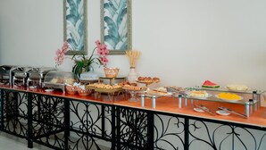 Een buffet met diverse gerechten, een decoratieve plant en een kunstwerk in een lijst aan de muur.