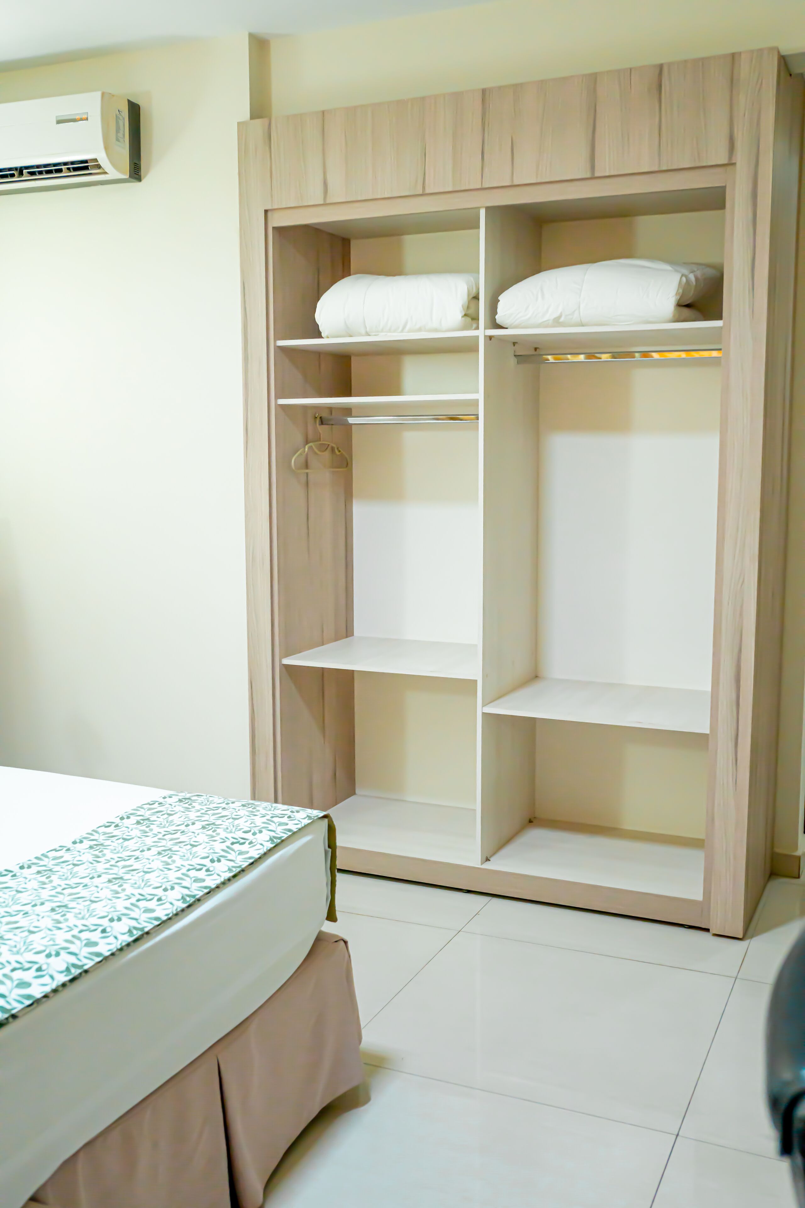 Un dormitorio con cama, un armario de madera con estantes múltiples y un armario colgante.