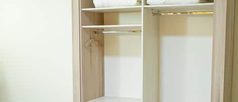 Un dormitorio con cama, un armario de madera con estantes múltiples y un armario colgante.